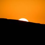 Stunning silhouette of a mountain ridge during a vibrant sunset with a glowing sky.